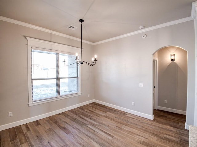 spare room with wood finished floors, arched walkways, and ornamental molding