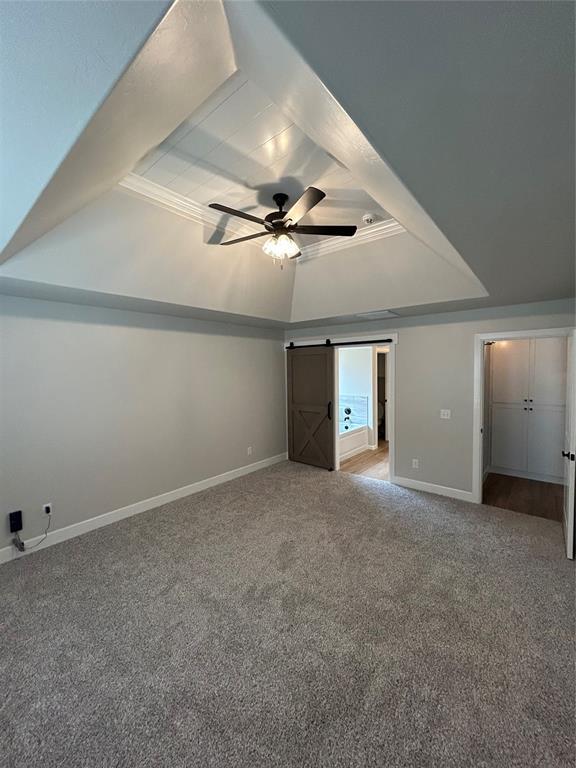 interior space featuring a barn door, baseboards, carpet floors, and ceiling fan