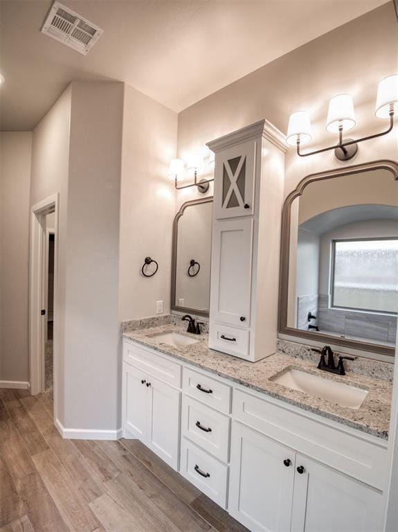 bathroom featuring a sink, visible vents, wood finished floors, and double vanity