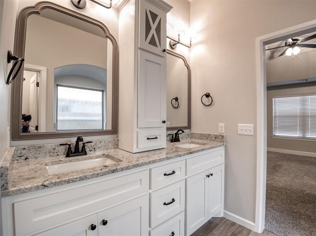 full bath with a sink, baseboards, a ceiling fan, and double vanity