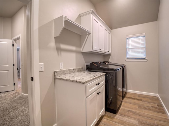 laundry room with cabinet space, baseboards, light wood finished floors, and washer and clothes dryer