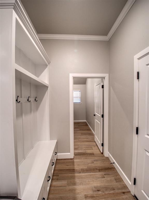 mudroom with ornamental molding, baseboards, and wood finished floors