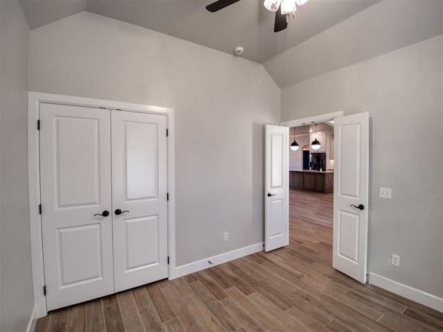 unfurnished bedroom featuring baseboards, a ceiling fan, lofted ceiling, and wood finished floors