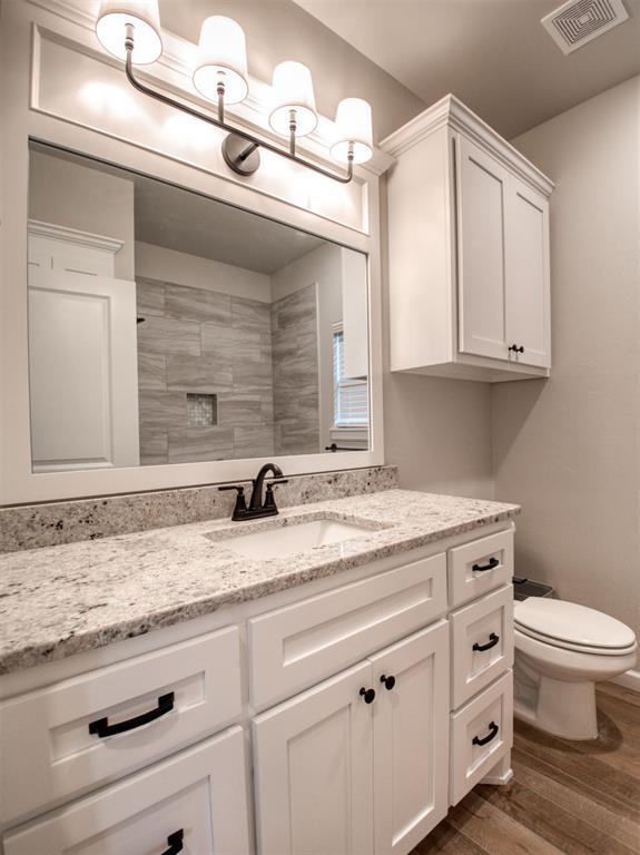 bathroom featuring visible vents, toilet, vanity, and wood finished floors