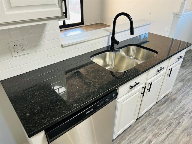 kitchen featuring white cabinetry, dishwasher, sink, tasteful backsplash, and dark stone countertops