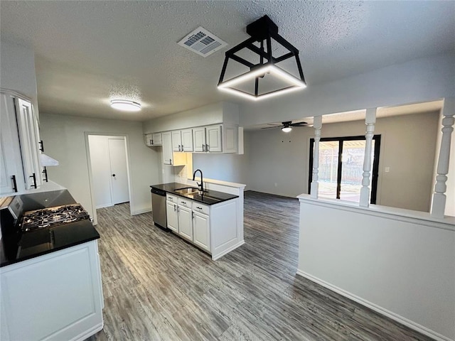 kitchen with stainless steel dishwasher, ceiling fan, white cabinetry, and a textured ceiling