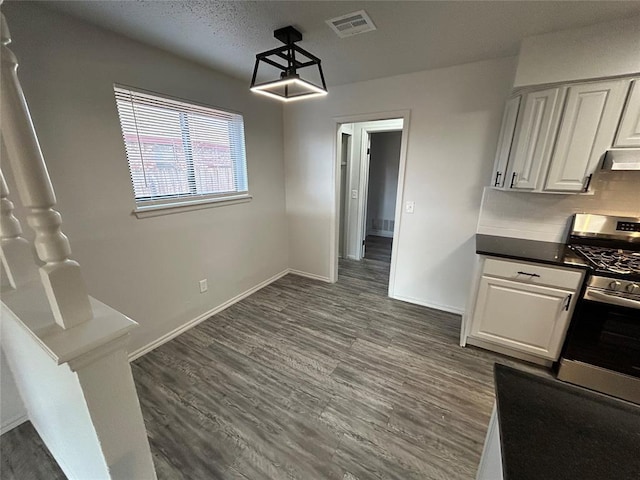 interior space with white cabinets, gas stove, extractor fan, and backsplash