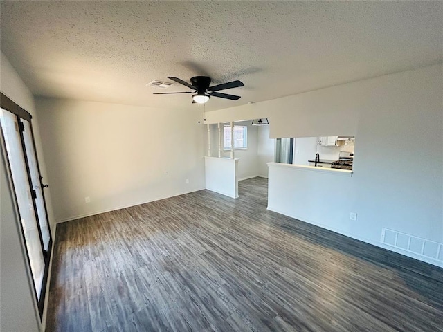 unfurnished living room with dark hardwood / wood-style flooring, a textured ceiling, and ceiling fan