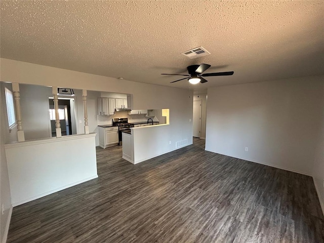 kitchen featuring kitchen peninsula, gas range, white cabinetry, and dark wood-type flooring