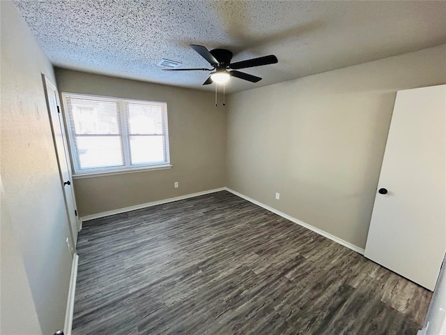 spare room featuring a textured ceiling, ceiling fan, and dark wood-type flooring