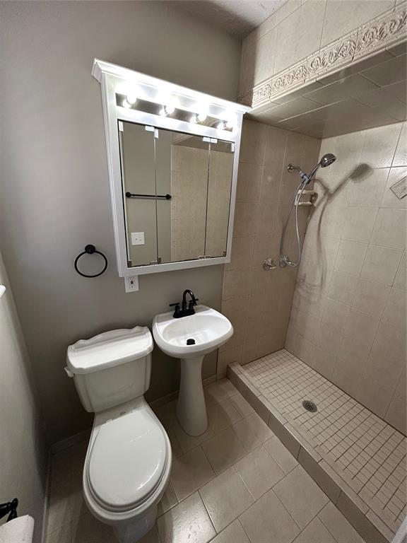 bathroom featuring tiled shower and toilet