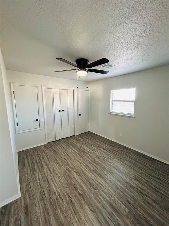 unfurnished bedroom featuring a textured ceiling, ceiling fan, and dark wood-type flooring