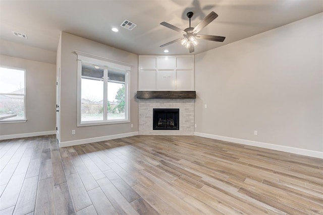 unfurnished living room with light hardwood / wood-style flooring, ceiling fan, and a tiled fireplace