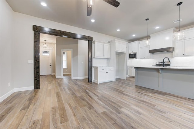 kitchen featuring white cabinets, hanging light fixtures, ceiling fan, light hardwood / wood-style floors, and stainless steel appliances