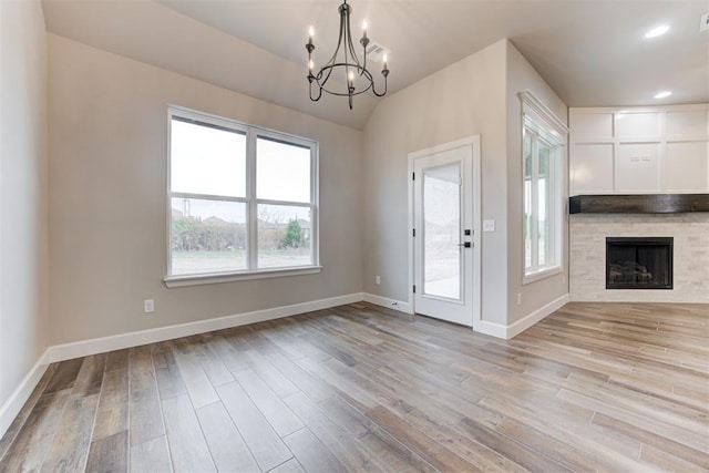 interior space featuring a notable chandelier, a fireplace, vaulted ceiling, and light hardwood / wood-style flooring