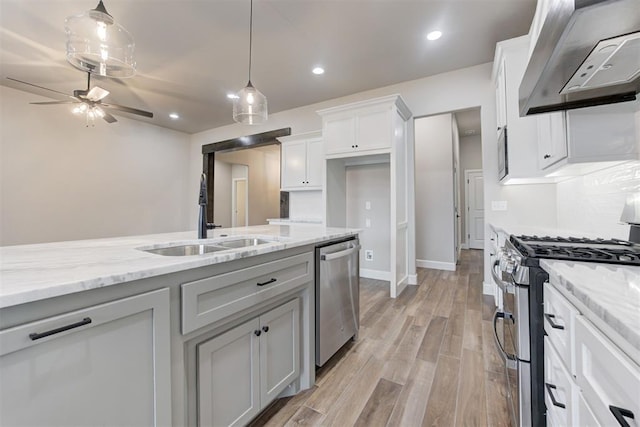 kitchen with white cabinets, sink, light hardwood / wood-style flooring, stainless steel appliances, and extractor fan