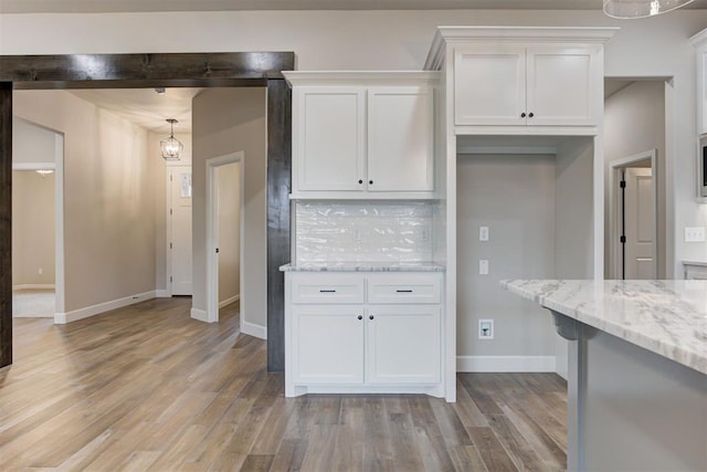 kitchen with decorative backsplash, light stone counters, white cabinets, and pendant lighting