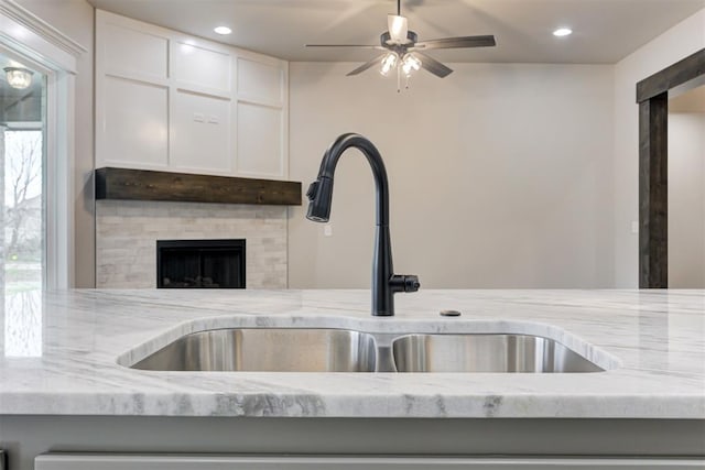 room details featuring light stone counters, sink, and white cabinets