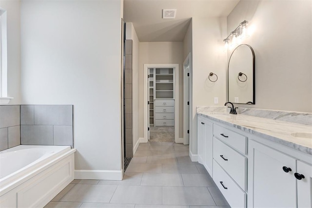 bathroom with tile patterned floors, a washtub, and vanity