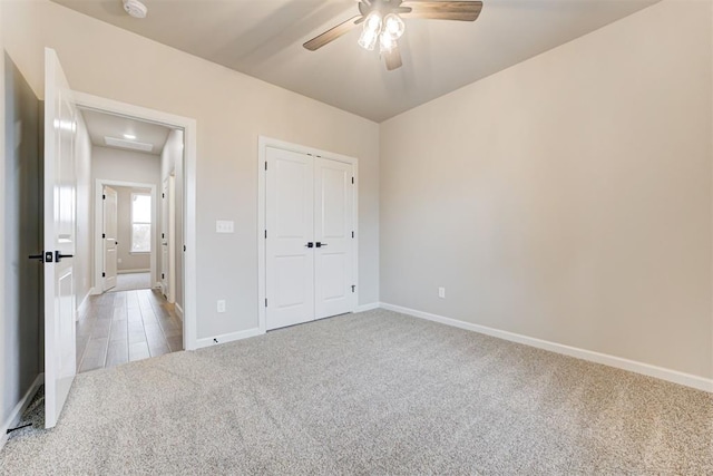 unfurnished bedroom featuring ceiling fan, light colored carpet, and a closet