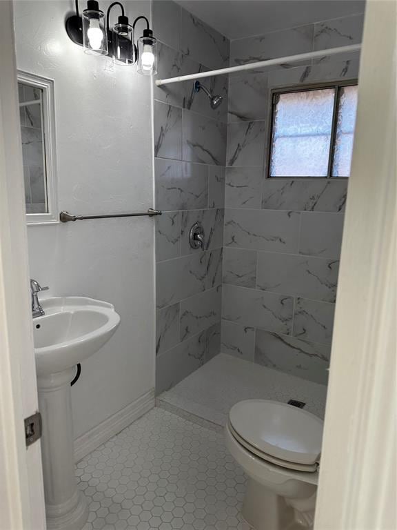 bathroom with tile patterned floors, toilet, a tile shower, and sink