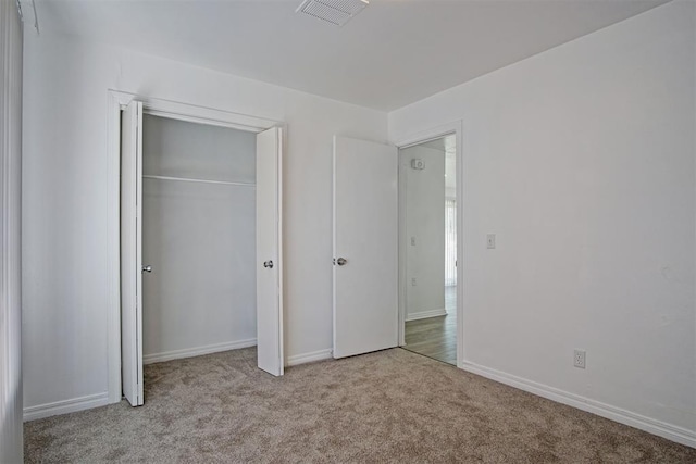 unfurnished bedroom featuring carpet flooring, baseboards, visible vents, and a closet