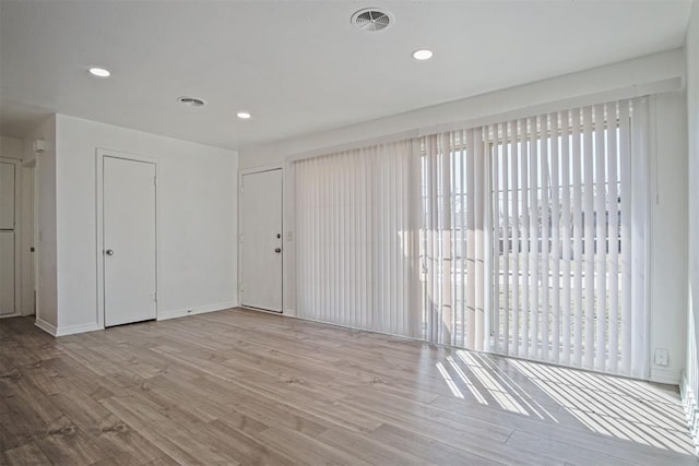 unfurnished room featuring recessed lighting, wood finished floors, visible vents, and baseboards