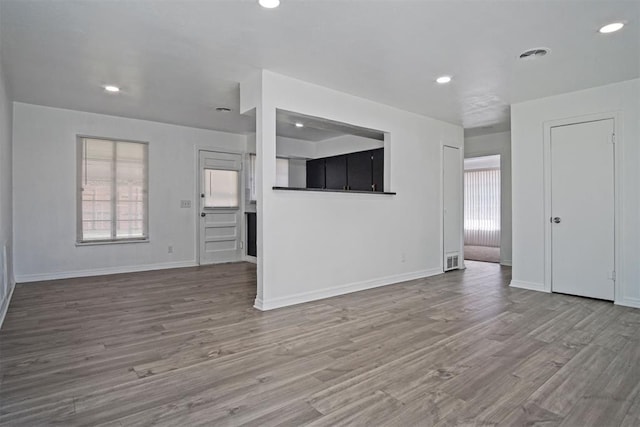 unfurnished living room with baseboards, a healthy amount of sunlight, and wood finished floors