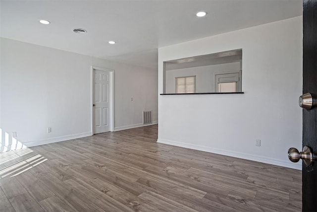 empty room featuring visible vents, recessed lighting, baseboards, and wood finished floors