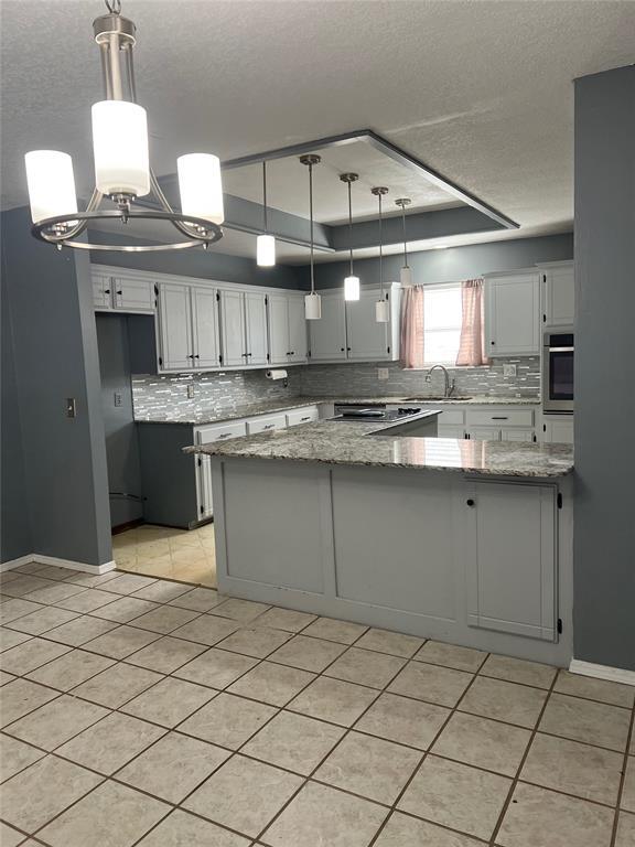 kitchen featuring pendant lighting, oven, light stone countertops, and light tile patterned floors