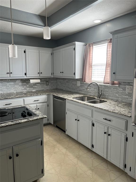 kitchen featuring black electric stovetop, stainless steel dishwasher, sink, pendant lighting, and white cabinetry