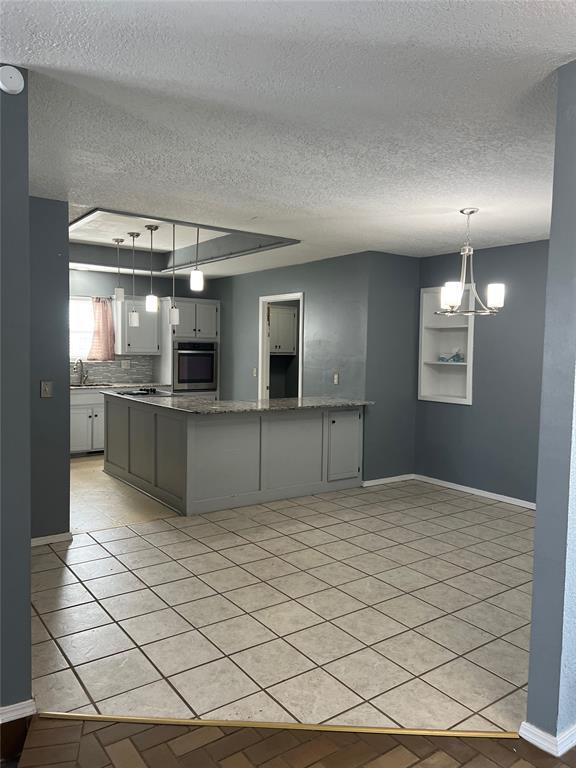 kitchen featuring decorative backsplash, sink, pendant lighting, and an inviting chandelier