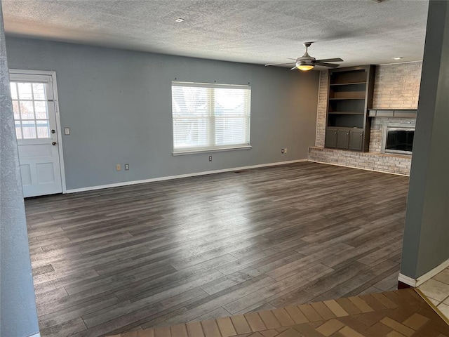 unfurnished living room featuring built in shelves, a wealth of natural light, a fireplace, and a textured ceiling