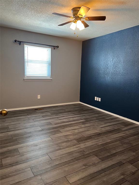 unfurnished room featuring ceiling fan, wood-type flooring, and a textured ceiling