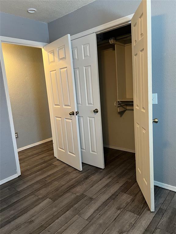 unfurnished bedroom featuring a textured ceiling, dark hardwood / wood-style flooring, and a closet