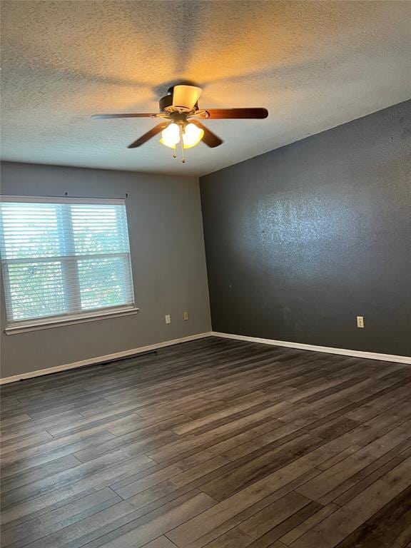 spare room with dark hardwood / wood-style floors, ceiling fan, and a textured ceiling