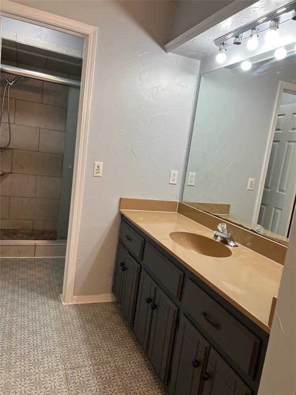 bathroom with vanity and tiled shower