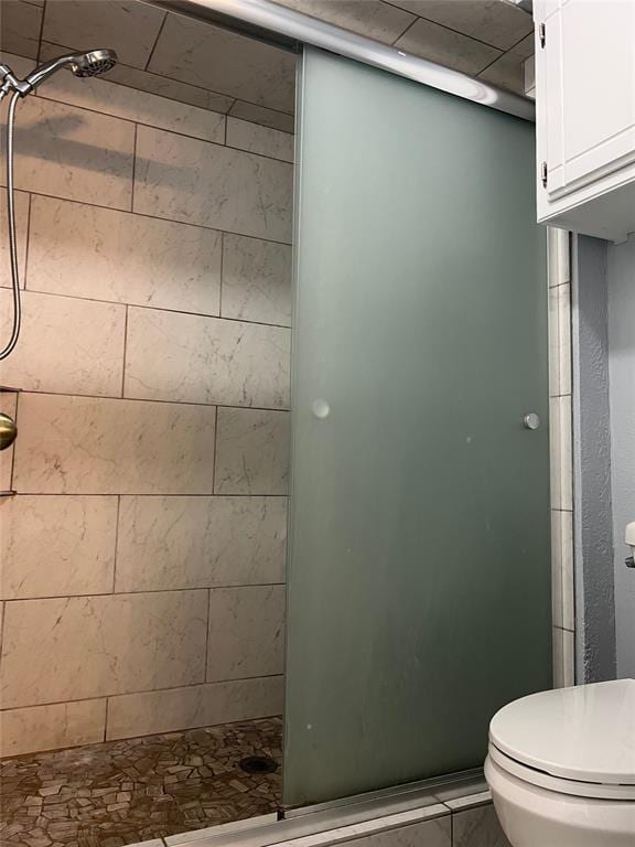 bathroom with a shower with door and toilet