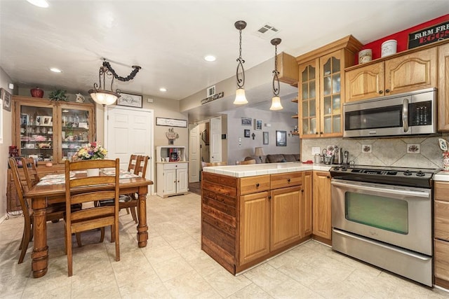 kitchen featuring decorative backsplash, appliances with stainless steel finishes, tile countertops, and hanging light fixtures