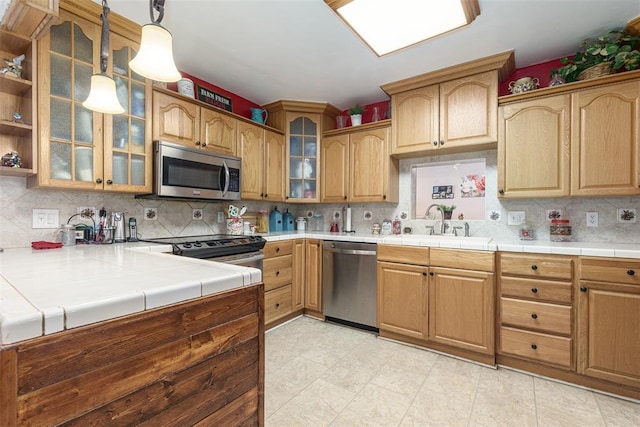 kitchen featuring appliances with stainless steel finishes, backsplash, tile counters, and sink