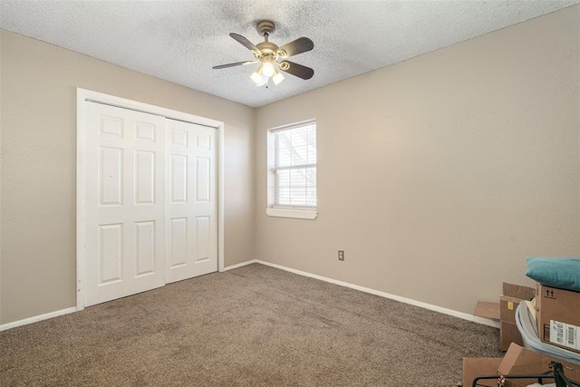 unfurnished bedroom featuring carpet flooring, a textured ceiling, a closet, and ceiling fan