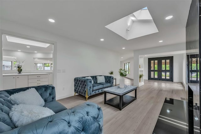 living room featuring french doors, light hardwood / wood-style flooring, and a skylight