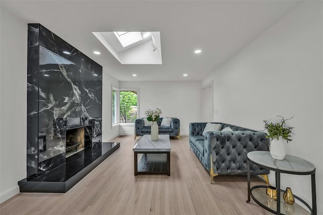 living room featuring a skylight, a premium fireplace, and light hardwood / wood-style floors