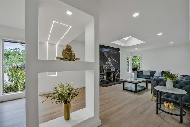 living room featuring a skylight, a premium fireplace, light wood-type flooring, and a wealth of natural light