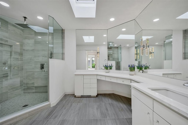 bathroom featuring vanity, a shower with door, and a skylight