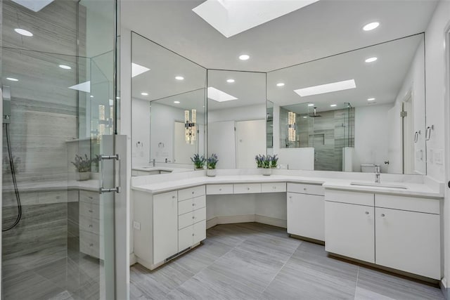 bathroom featuring a skylight, vanity, and a shower with shower door