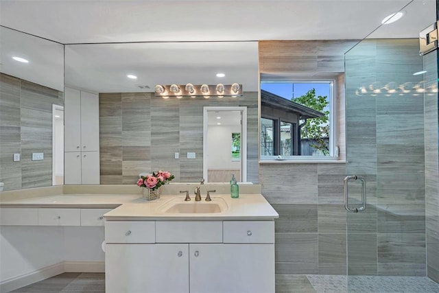 bathroom with vanity, tile walls, and a shower with shower door