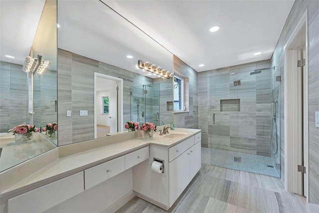 bathroom featuring vanity, a shower with shower door, and tile walls