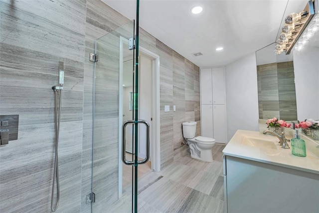 bathroom with walk in shower, vanity, toilet, and tile walls