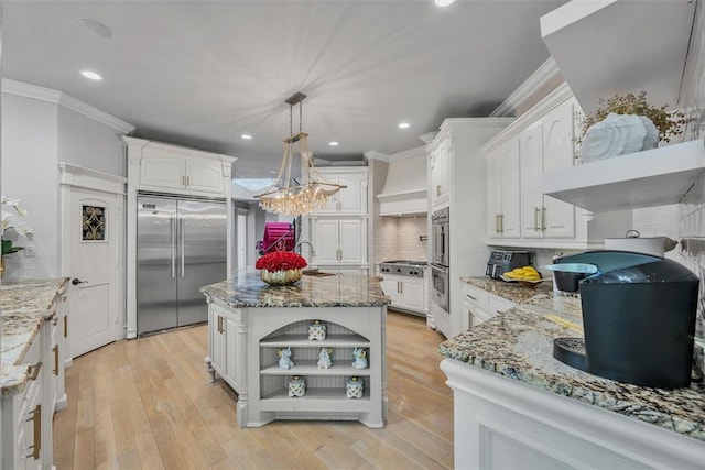 kitchen featuring pendant lighting, backsplash, a kitchen island, white cabinetry, and stainless steel appliances